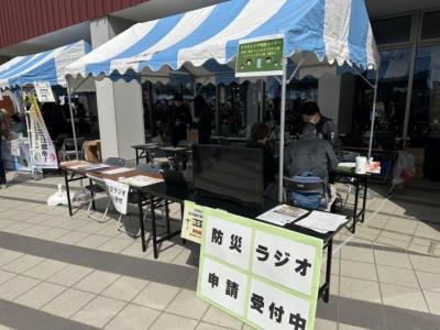 テントのしたで防災ラジオの受け付けをしている