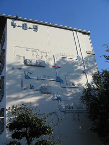 室外機や配管にキッチン道具や瓶が置かれている立体アート
