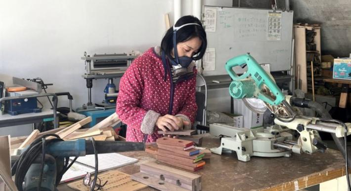 つちやさんが井野アーティストヴィレッジのアトリエで木片を加工し作品を制作している様子