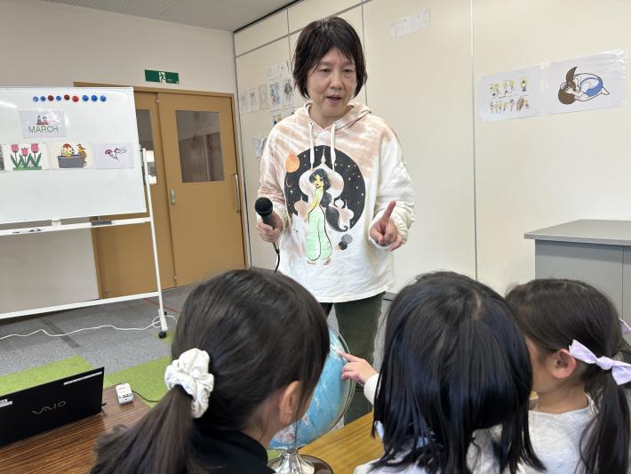 地球儀と子どもの前で話をする女性
