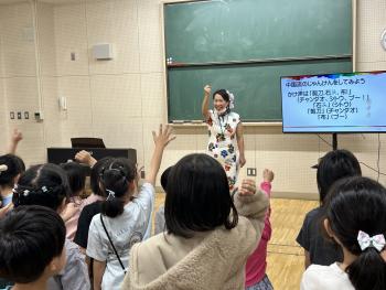 チャイナドレスを着た女性が子どもたちとじゃんけんをしている