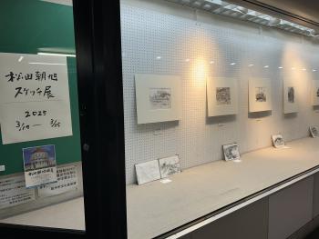 松田朝旭スケッチ展と書かれた紙の横に、スケッチ作品が一列に飾られている。