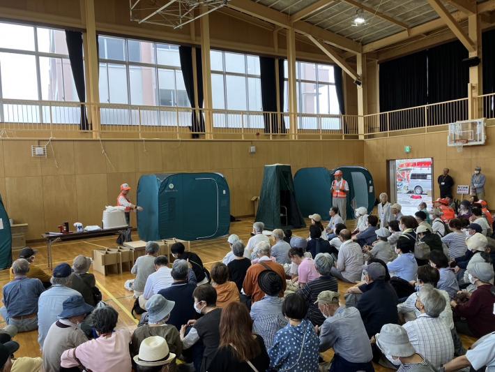 仮説テントを見る体育館に集まった大勢の男女