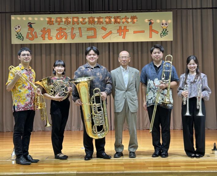 ステージ上で楽器を持って立つ大学生たち