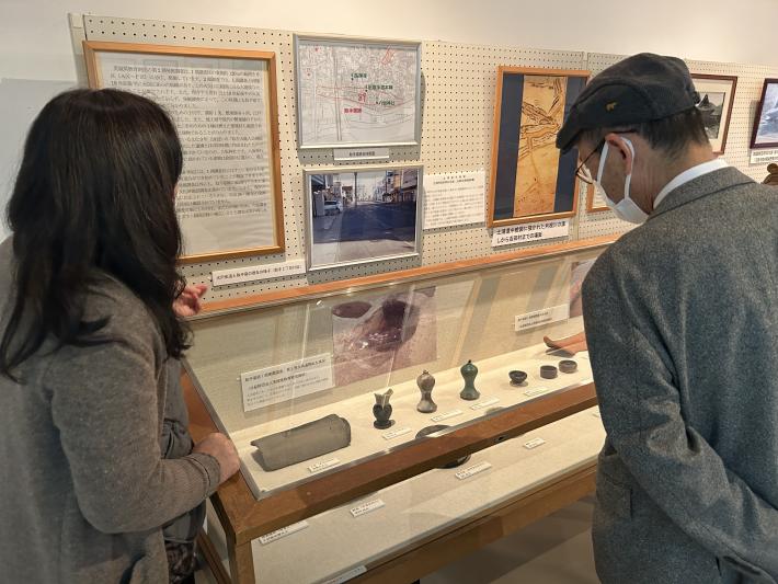 出土品を見る男性と解説する女性