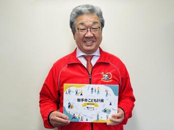 取手市こども計画を持った赤いジャンパーを着た男性