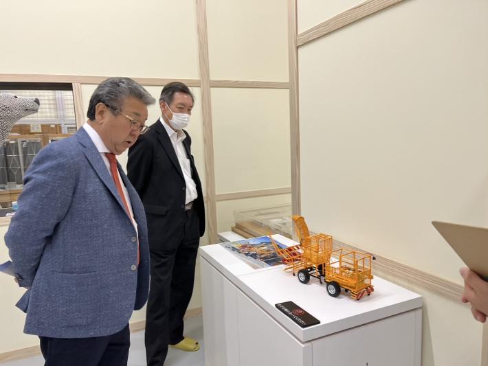 机に置いてあるアート作品を見る男性2名
