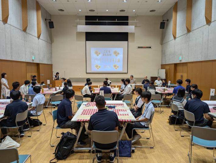 とりでこども未来会議と書かれたスクリーンがある会場で着座する大勢の人たち