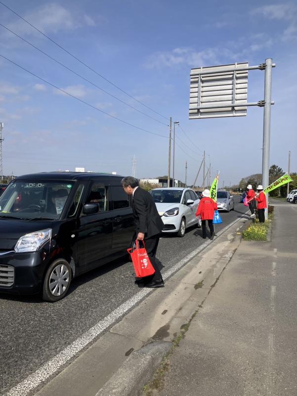 車に乗った人に、車の窓から啓発品を渡す男性