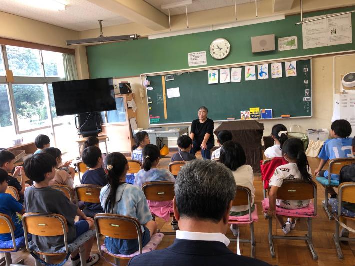 子どもたちは女性がお話の朗読をするのを聞いている