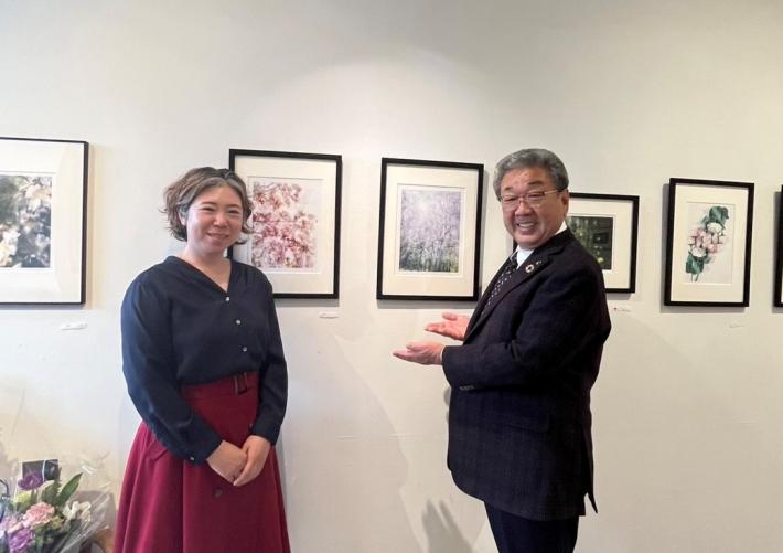 男女が写真作品の前に並んでいる
