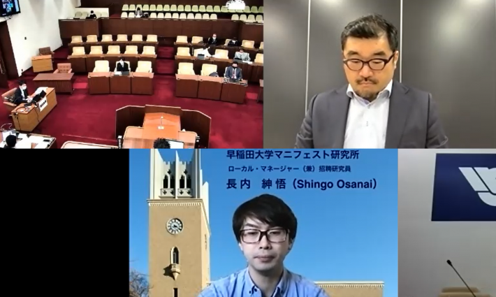 画面が3分割され、議場の様子と眼鏡をかけたスーツ姿の男性2名がそれぞれ映っている