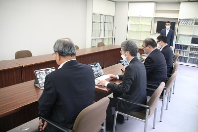 横一列に議員4人が座る。一人一台タブレットがあり、それぞれがオンライン会議に入る。一番奥に事務局職員1人が立つ
