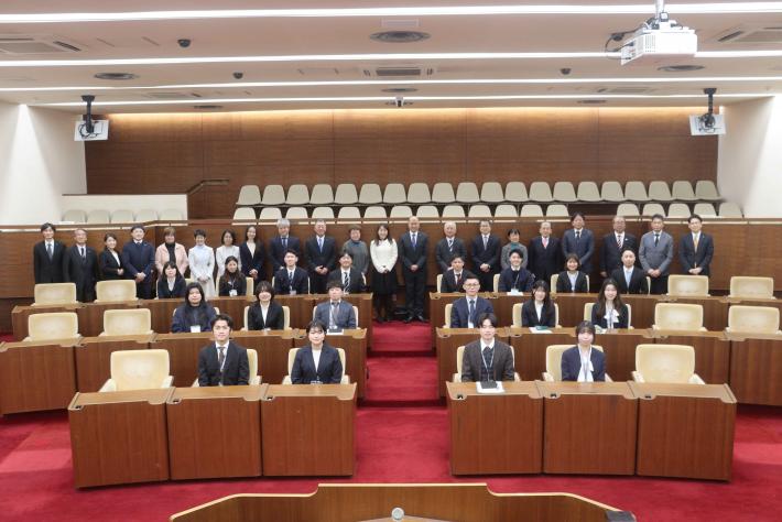 新規採用職員と議員らが取手市議会議場で記念撮影をしている様子