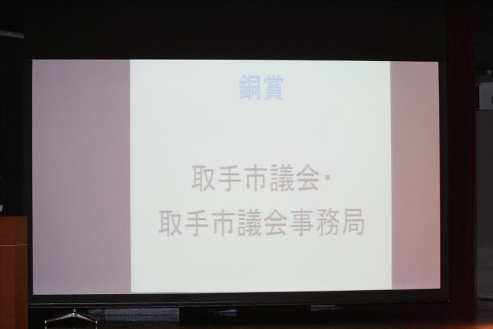 「銅賞、取手市議会、取手市議会事務局」と表示されたスクリーンが置いてある