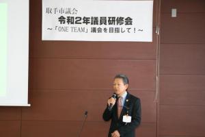 議会事務局長による終わりの挨拶。壁に「取手市議会令和2年議員研修会ワンチーム議会を目指して」の横断幕が掲げられている。