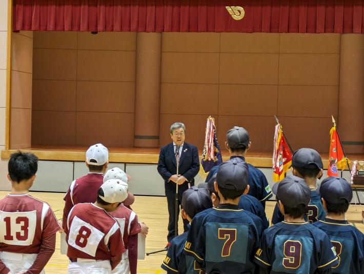 ステージ前にて挨拶をする市長。市長の前に整列する野球のユニフォーム姿の少年達