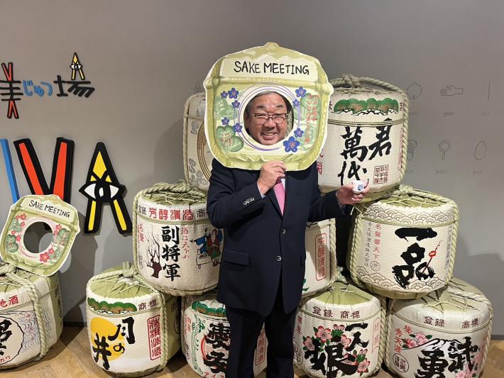 アトレ取手ホールにて酒樽の前で顔出しパネルから顔を出す市長