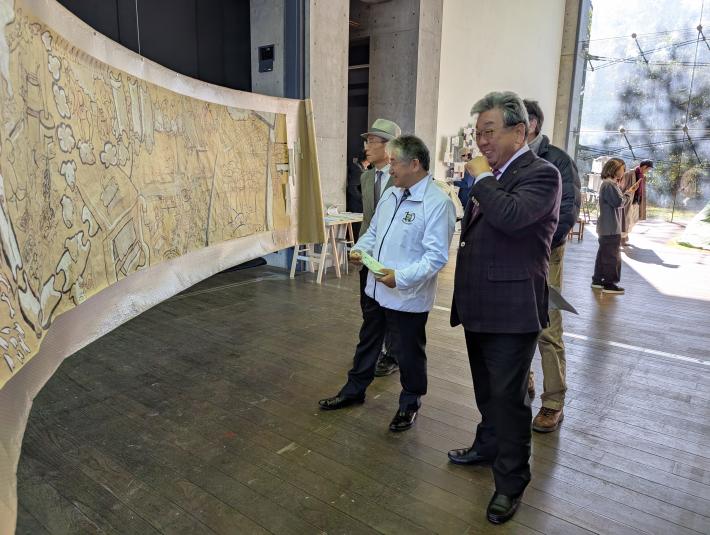 横長の絵巻のようなアートを鑑賞する男性たち