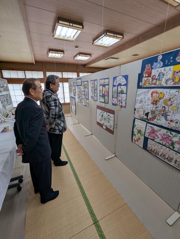 壁掛けの作品を鑑賞する男性たち
