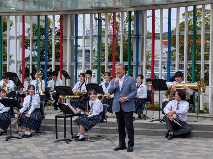 吹奏楽部の中学生徒の横で挨拶をする市長