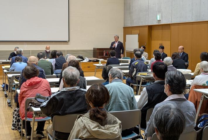 着座の参加者の前で発言をする市長