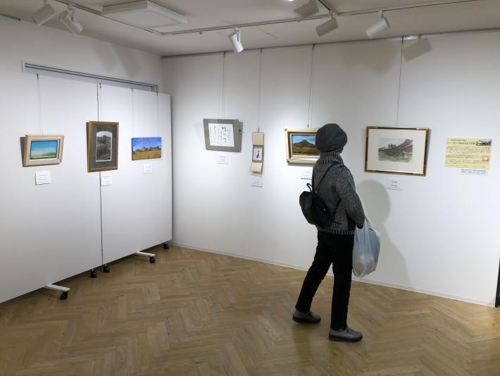 壁にかかった展示品を鑑賞する女性。