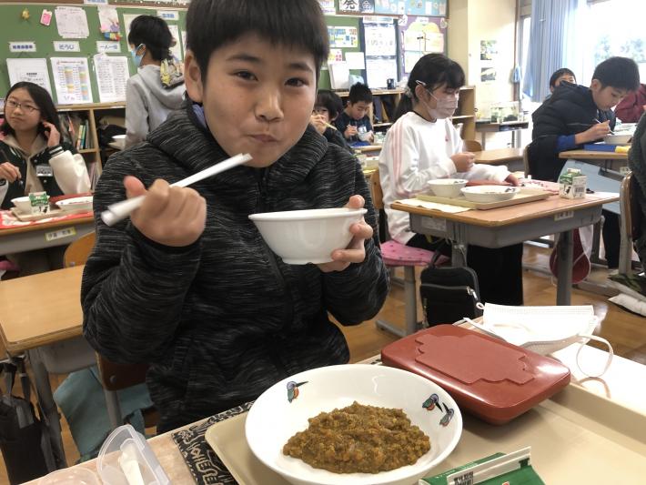 給食を笑顔で口に運ぶ男の子