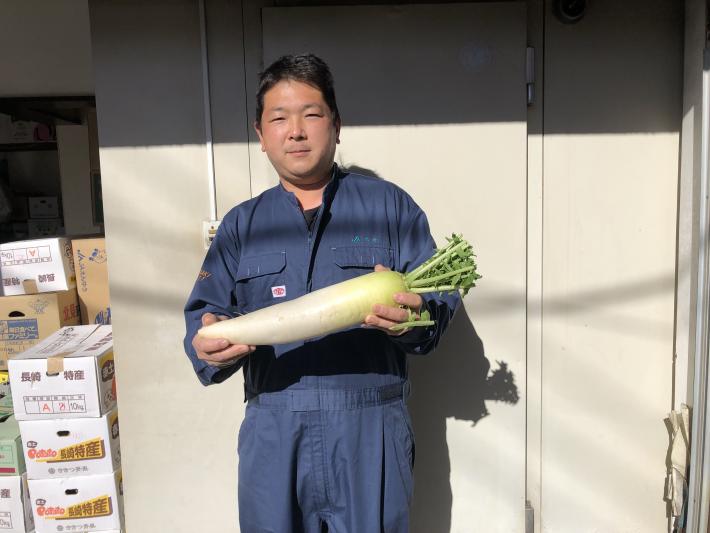 大根を持ち作業着を着た男性