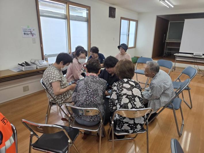 双葉地区の住民の皆さんのグループに市職員が入り、スマホ操作を説明している様子