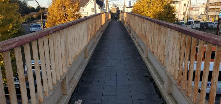 横断歩道橋を橋の上から見た施工前の写真。錆ついている状態。