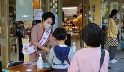 お子さんに対して目線を下げ、冊子をテーブル越しに手渡す若い女性の写真