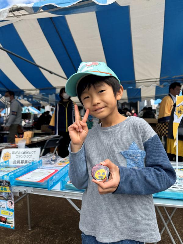男の子がピースをして作った缶バッジを見せている。