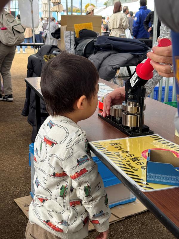 男の子がたって、缶バッジマシーンを見つめている