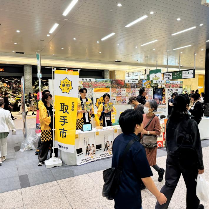 大宮駅構内に人が行き交う中にある黄色の「取手市」のぼり旗がある取手市のブース