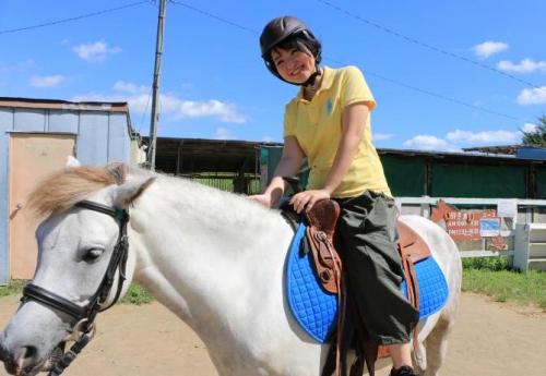 馬にまたがって背中の上で笑顔を見せている若い女性