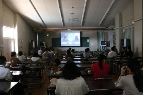 暗い部屋で投影された映画を見ている人たち。