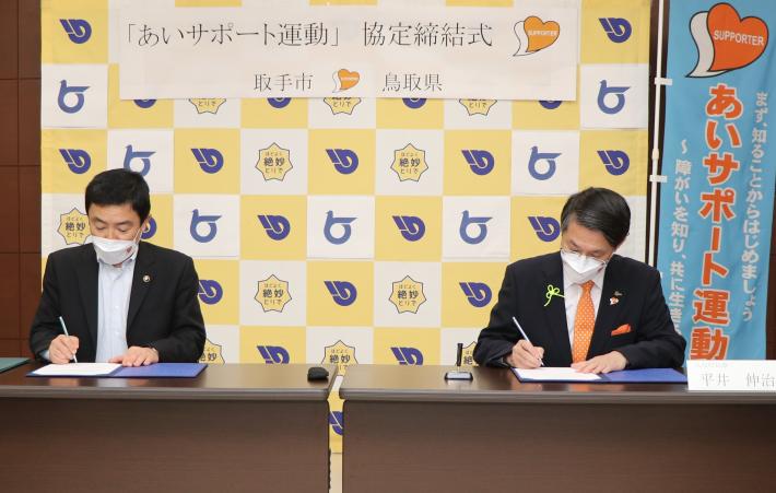 藤井元市長と平井鳥取県知事が協定書に署名している写真