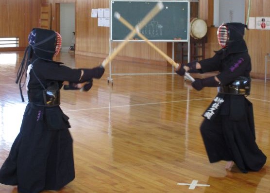 面の打ち合い。体育館様の場所で、面を打ち合う2人の剣士。